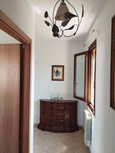 Un pasillo con un espejo, una cómoda y una lámpara de araña. en Casa vacanze Sara, en Gagno