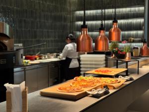 a woman in a kitchen with pizzas on a counter at OREA Resort Sklář Harrachov in Harrachov