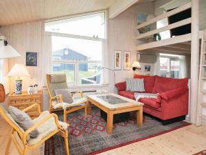 ein Wohnzimmer mit einem roten Sofa und Stühlen in der Unterkunft 6 person holiday home in Blokhus-By Traum in Blokhus