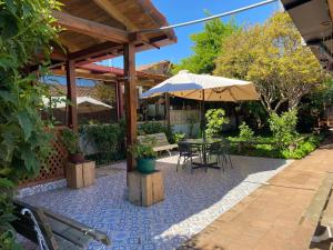 a patio with a table and an umbrella at Hotel Los Artesanos in Villa Alegre