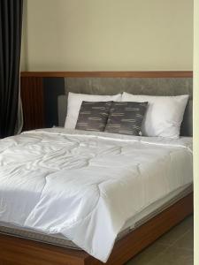 a bed with white sheets and pillows on it at Sun Executive Villas Sanur in Mantaak