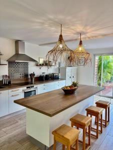 eine Küche mit weißen Schränken und einer großen Insel mit Hockern in der Unterkunft Tropical Pool Villa in Orient Bay