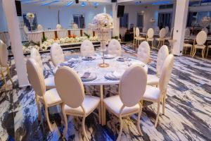 a table set up for a wedding with white chairs and flowers at Hôtel Exotic Plaza in Douala