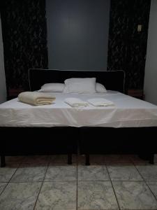 a black bed with white sheets and pillows on it at Pousada Roosevelt- suíte 1 in Uberlândia