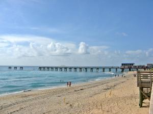 a beach with a pier and people in the water at Private home in West Palm in West Palm Beach