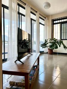 a living room with a tv and some windows at Tai Africa Apartment in Arusha