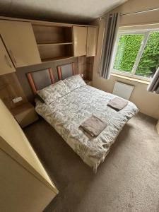 a small bedroom with a bed and a window at The Lake District Caravan in Lamplugh