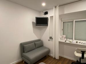 a living room with a chair and a tv on the wall at Casa da Covilhã - Pedra e Lã in Covilhã