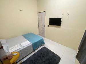a bedroom with a bed and a tv on the wall at Recanto Buriti in Barreirinhas
