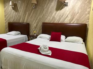 a bedroom with two beds with red and white sheets at Hotel Marina Centro in San Pedro Sula