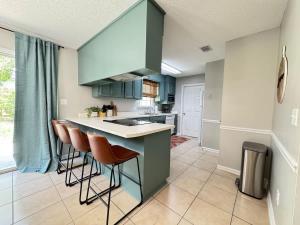 una cocina con armarios azules y taburetes de bar en Big Sky Bungalow - 5 Beds Sleeps 8, en Valdosta