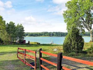 a red fence with a view of a lake at 5 person holiday home in VÄDDÖ in Veda