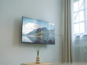 a flat screen tv hanging on a wall next to a window at Einzigartiges Scandi-Apartment in der Innenstadt ruhig, stilvoll & mit WLAN in Riedlingen