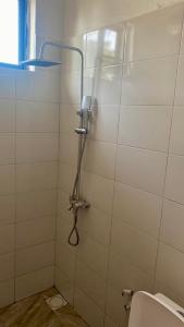 a shower in a white tiled bathroom with a toilet at Villa Katerina Kendwa in Kendwa +25 photos