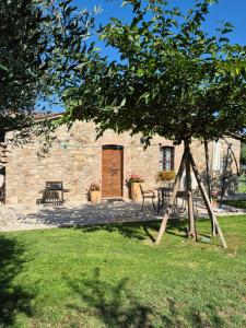 a stone building with a bench and a tree at Agriturismo Case Corboli villetta Rufino in Todi