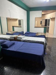 three beds in a room with blue sheets on them at EcoRally Stay in Bella Vista