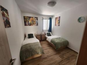 two beds in a room with white walls and wood floors at Apartment Golden Oak in Dubrovnik