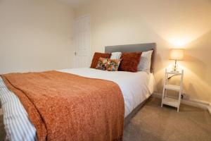 a bedroom with a large bed with a orange blanket at Three Bedroom House By Brookland Stays Serviced Accommodation Short Lets Cheltenham With Free WiFi in Cheltenham