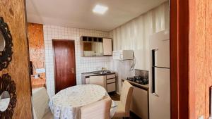 a small kitchen with a refrigerator and a table at Loft pertinho do Aeroporto de Navegantes! in Navegantes +4 photos