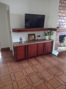 un soggiorno con una TV a schermo piatto su una parete di Casa geminada com piscina exclusiva ad Arroio do Sal