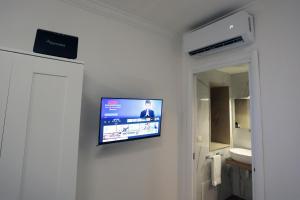 a flat screen tv hanging on a wall in a bathroom at Casa Noal - a due passi da Ortigia e dal mare in Syracuse