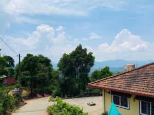 - une vue sur une maison avec des arbres et des montagnes en arrière-plan dans l'établissement The Sunset Canopy Coorg homestay, à Madikeri