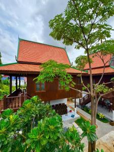 a house with a red roof and a tree at Sala Khmer - Traditional Wooden House & Garden in Siem Reap