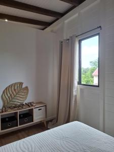 a white bedroom with a bed and a window at Bungalow cocon des alizés in Les Abymes