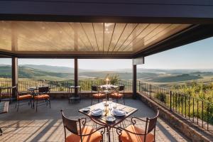 a patio with tables and chairs and a view of the mountains at Capanna Suites in Montalcino