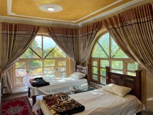 a bedroom with two beds and large windows at Kabul Qargha Palace Hotel, Restaurant and wedding Hall in Kabul
