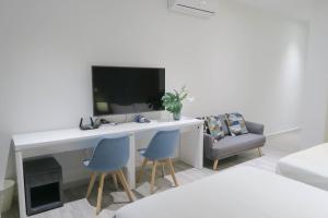 a room with a desk with two chairs and a tv at RR Cozy Studio & Suite in Singapore