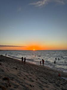 eine Gruppe von Menschen am Strand bei Sonnenuntergang in der Unterkunft Chalé Levi BG in Barrinha + 3 Fotos