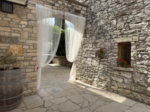 a window with white curtains in a stone building at Relais Borgo San Nicolò in Umag