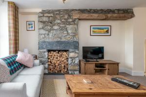 a living room with a stone fireplace with a television at Glasfryn Cottage Dolgellau in Dolgellau