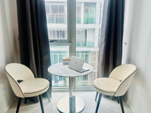 a table with two chairs and a laptop on it in front of a window at Hyde Sukhumvit 11 Bankok in Bangkok