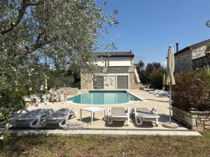 a swimming pool with lounge chairs and a house at Relais Borgo San Nicolò in Umag