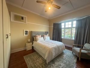 a bedroom with a bed and a ceiling fan at Glenwood Cottage 5km from beach, Art gallery, with garden and pool in Durban +41 photos
