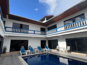 a villa with a swimming pool and blue chairs at Treff nad phop hotel in Patong Beach