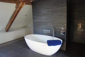 a white bath tub sitting in a bathroom at Annecy LakeLodge Lakeside Modern 7 bedroom Retreat in Doussard +18 photos