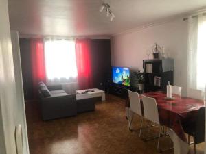 a living room with a table and a couch and a television at Grande maison avec jardin a proximité centre ville in Laval