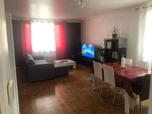 a living room with a table and a couch and a television at Grande maison avec jardin a proximité centre ville in Laval