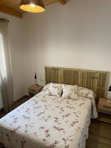 a bedroom with a bed with a floral comforter at La Casa Del Sastre in Torrecilla de los Ángeles