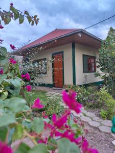 a small house with pink flowers in front of it at Hospedaje Cattleya in Oxapampa +5 photos