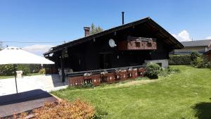 a black building with a balcony on a yard at Chalet familial au cœur de la Haute Savoie in La Roche-sur-Foron