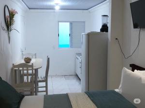 a bedroom with a bed and a kitchen with a table at Pousada Caravela in Penha