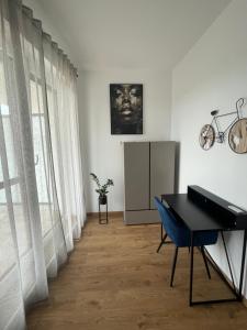 a room with a piano and a desk and a window at Riverside Apartment Szeged in Szeged