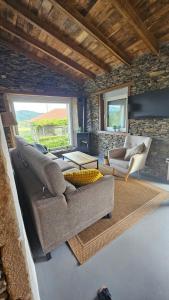 a living room with two couches and a stone wall at CASA DO XASTRE in Arnego