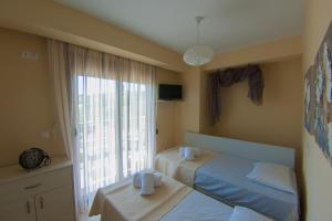 a bedroom with two beds and a large window at Ianthi Maisonettes in Nea Roda