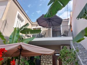 a balcony with tables and chairs and an umbrella at Stone-built Villa Nesseris 80 m2 in Preveza