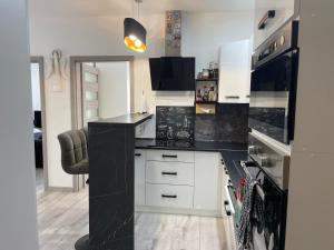 a kitchen with white cabinets and black counter tops at Apartmán SIA Garážové parkovanie in Poprad